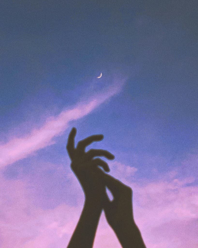 Hands reaching toward a crescent moon
